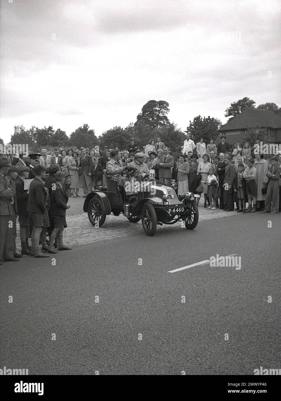 1950s, historical, a crowd watching an open-top vintage car, No 39, registration P 4460, no doors, drive off at the start of a vintage car run, England, UK. Motor cars built before WW1 are generally considered veteran cars, although the strict interpretation is that only cars built pre 1904 can be called veteran cars and that cars built between 1905-1918 should be referred to as Edwardian cars. Cars made beween 1919 and 1930 are generally classified as vintage. Stock Photo