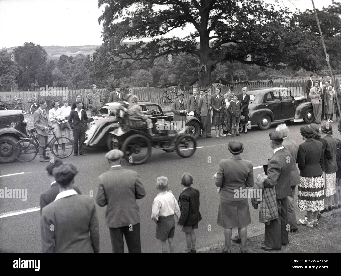 1950s, historical, spectators standing roadside watching an open-top veteran car taking part in a vintage car run, England, UK. Stock Photo