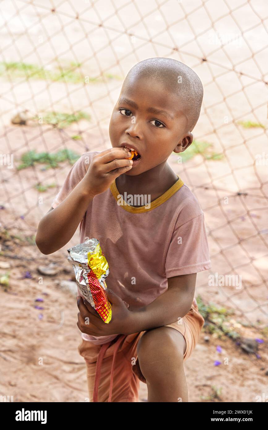 hungry young african child eating snacks, village life in a remote area Stock Photo
