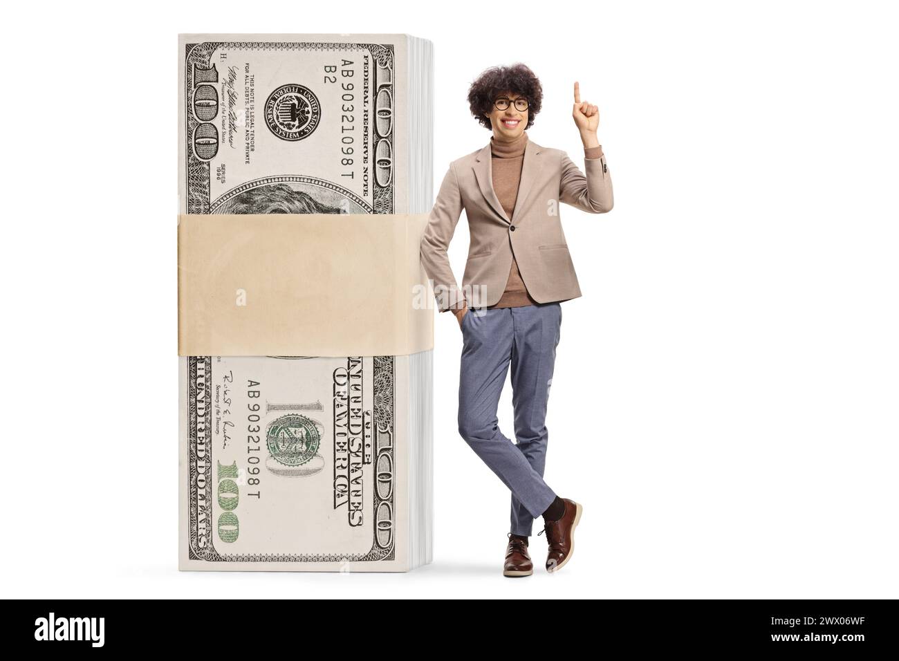 Young man next to a stack of money standing and pointing up isolated on white background Stock Photo