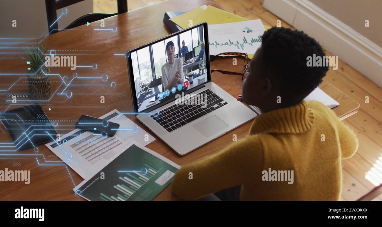 Image of microprocessor connections over african american woman having a image call on laptop. Global networking and business technology concept Stock Photo