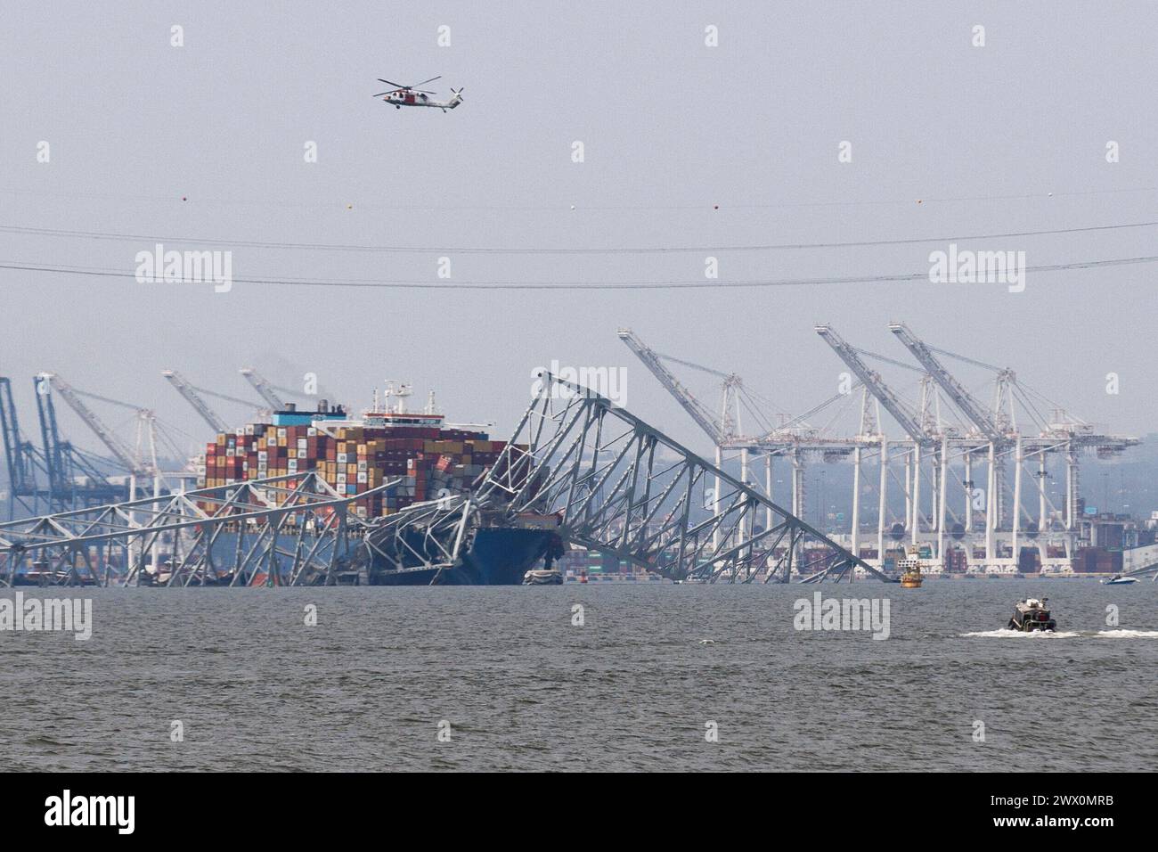 A helicopter searches for people trapped under the remains of Francis Scott Key Bridge outside Baltimore, Maryland after a container ship lost power and struck the bridge in the early morning hours on Tuesday, March 26, 2024. Credit: Aaron Schwartz/CNP Stock Photo