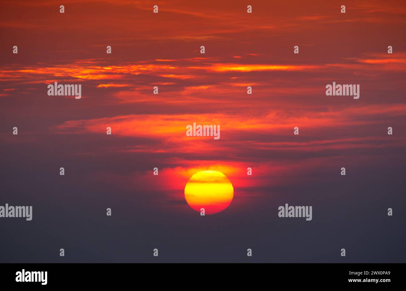 Image of the sun rising as an orange globe in lines of cloud at Doi Pha Hom Pok national park, Chiang Mai, Thailand Stock Photo
