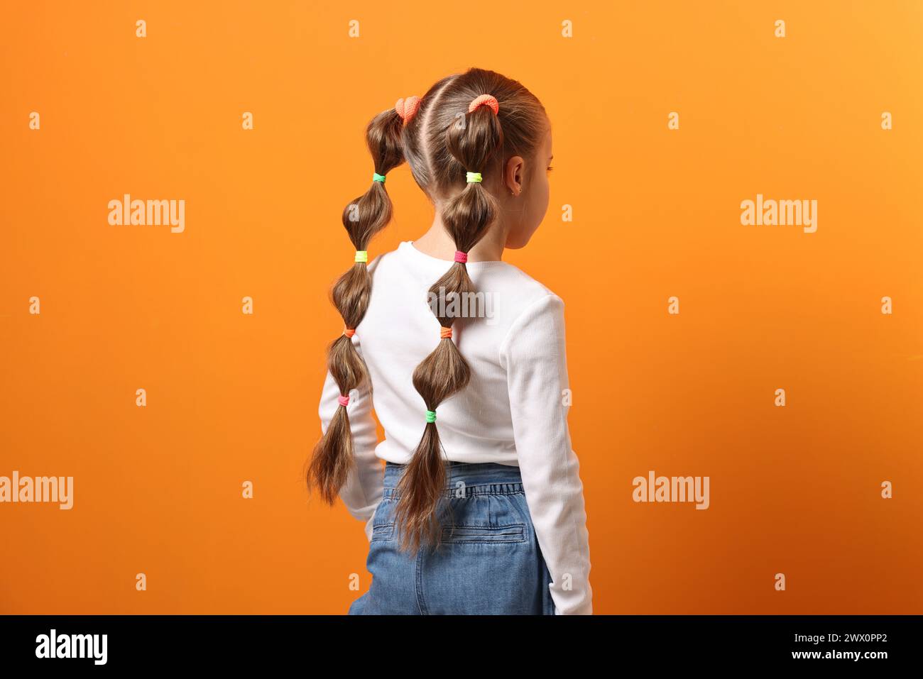 little-girl-with-beautiful-hairstyle-on-orange-background-back-view