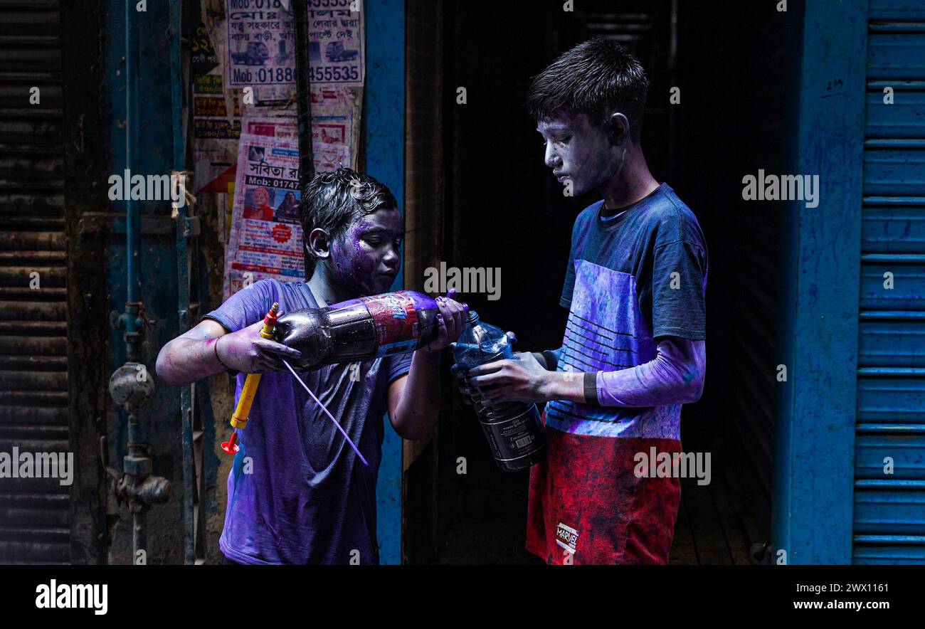 Dhaka, Bangladesh . 26th Mar, 2024. March 26, 2024, Dhaka, Bangladesh: Two young from the Hindu community with their faces painted, mix powder colors inside a bottle to paint persons to celebrate the Dol Purnima festival know as Holi Festival at Sakhari Bazar. on March 26, 2024 in Dhaka, Bangladesh. (Photo by Nahid Hasan/ Eyepix Group/Sipa USA) Credit: Sipa USA/Alamy Live News Stock Photo