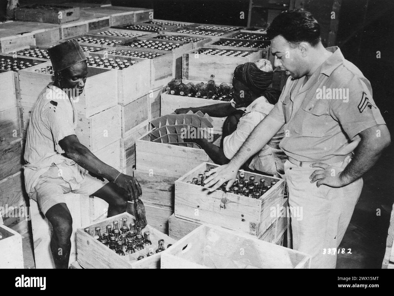 Original Caption: 'India. Tec 5 Max Nahman of New Brunswick, N.J. supervises the Coca Cola packing department.' ca. October 1942 Stock Photo