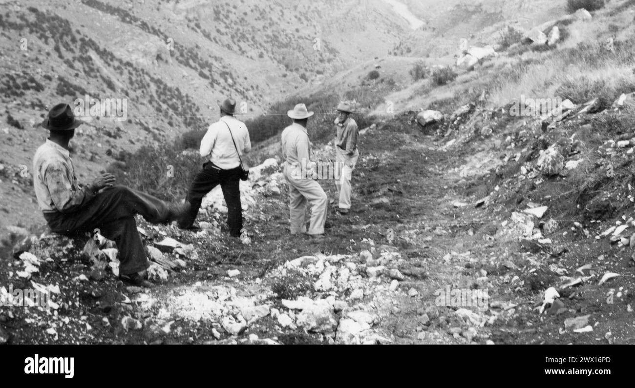 Men in a rocky valley in Wyoming wearing cowboy hats, one man has a camera case ca. 1938-1948 Stock Photo