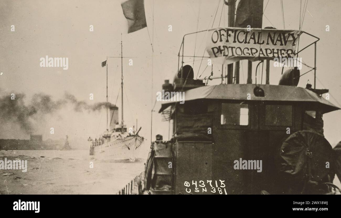 The tugboat that carried the official Navy photographers during the Naval Review in North River. The U.S.S. Mayflower following behind ca. December 1918 Stock Photo