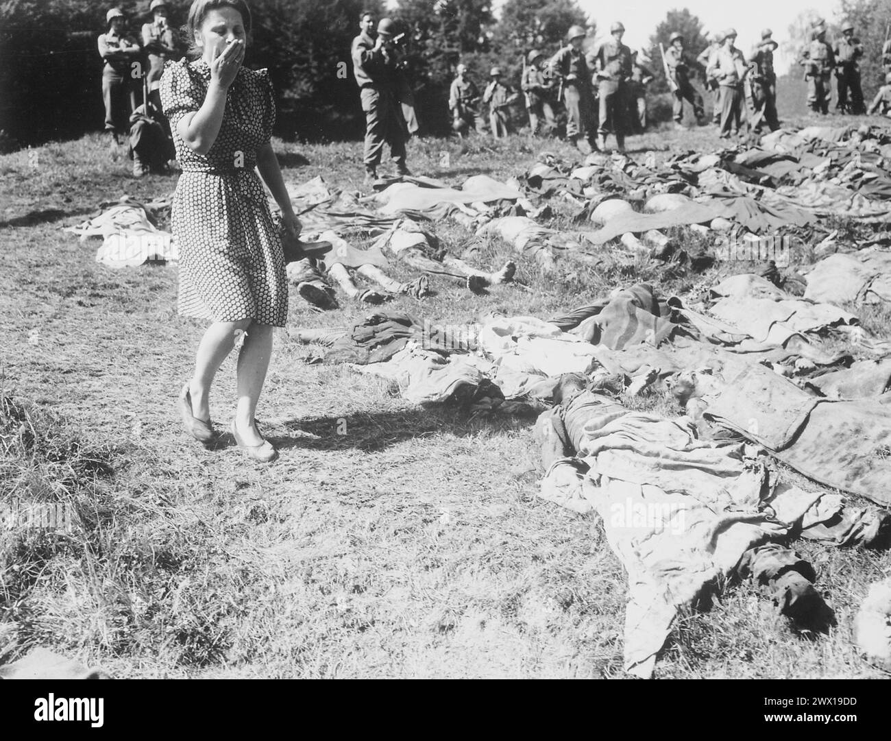 A German girl is overcome as she walks past the exhumed bodies of some of the 800 slave workers murdered by SS guards near Namering, Germany, and laid here so that townspeople may view the work of their Nazi leaders ca. May 17, 1945 Stock Photo