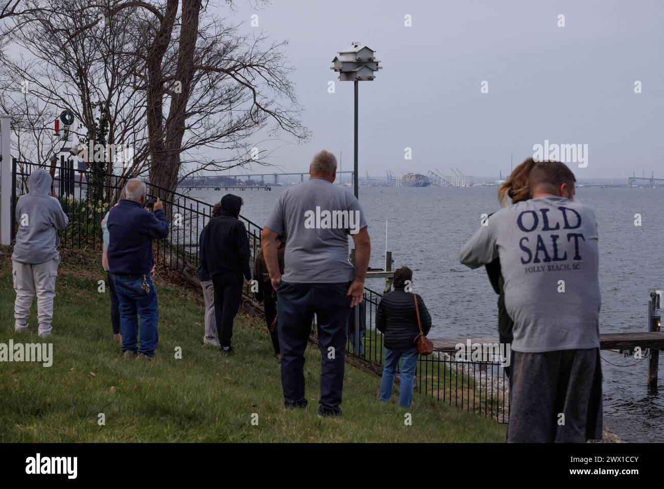 Onlookers view rescue efforts by authorities, as they search for people trapped under the remains of Francis Scott Key Bridge outside Baltimore, Maryland after a container ship lost power and struck the bridge in the early morning hours on Tuesday, March 26, 2024 in Baltimore, MD, USA. Six people are missing and presumed dead after a container ship hit the landmark Francis Scott Key Bridge in the US city of Baltimore. The Coast Guard said it had suspended its search and begun a recovery effort. Several vehicles were crossing the bridge, which is more than 2.6km (1.6 miles) long, when it collap Stock Photo