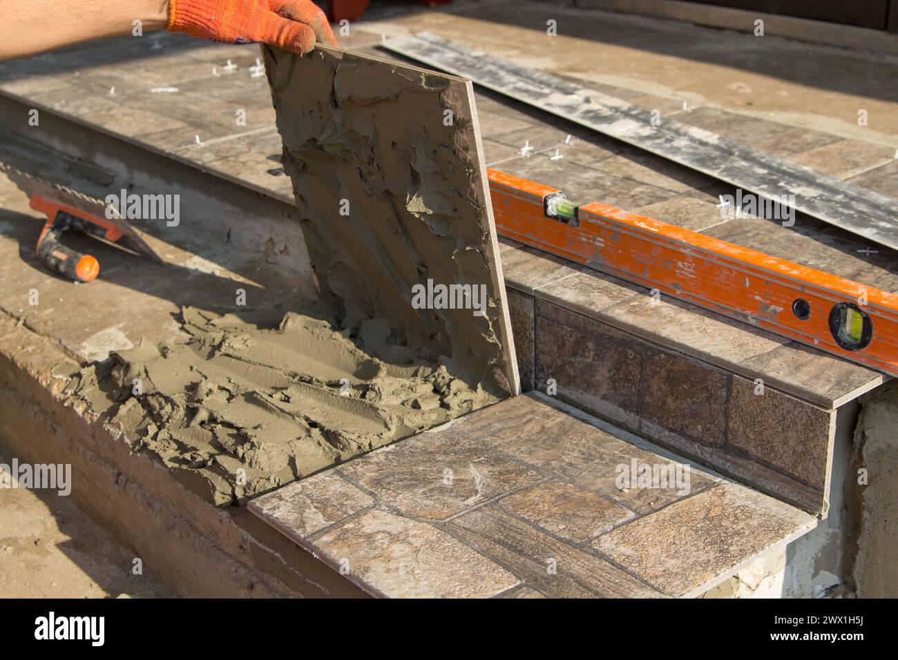 The builder works on stairs puts a tile of stone on the stairs to the office Stock Photo