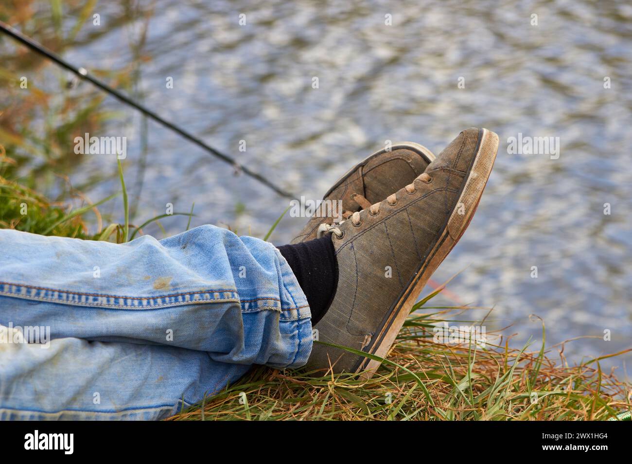 autumn fisherman catches fish sitting on the shore of the pond Stock Photo