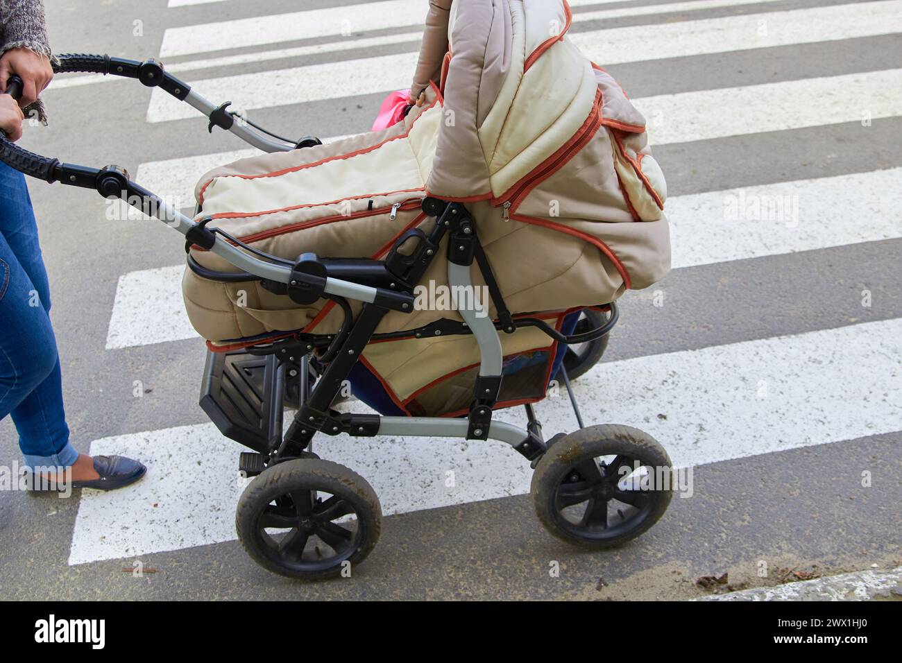 woman on the street pushes an old stroller on the road Stock Photo