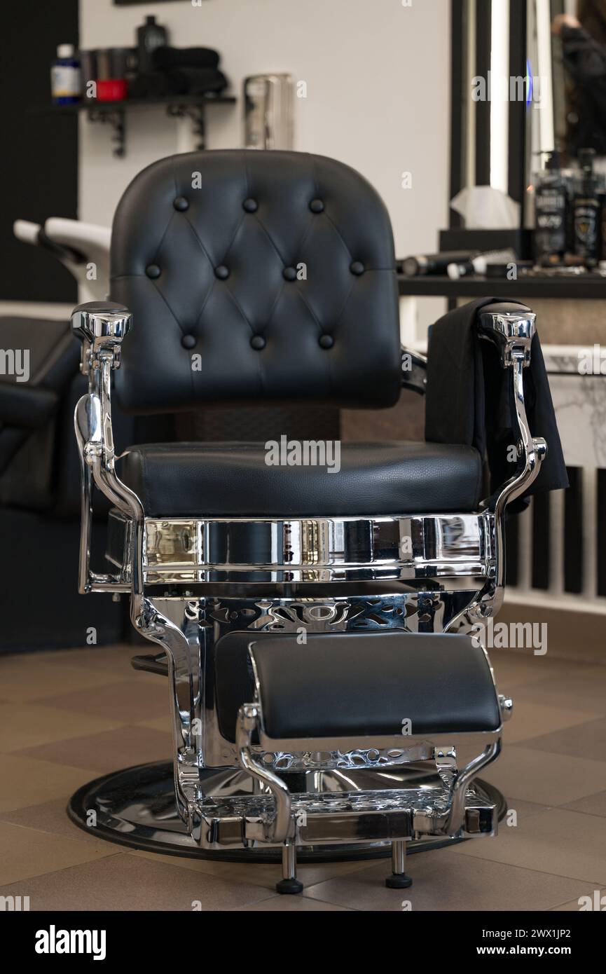 Barber chair made of black leather and chrome elements. Front view of the new chair in the barbershop. Stock Photo