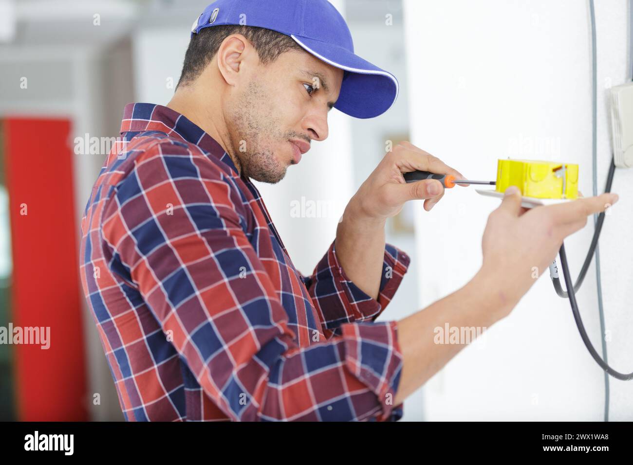electrician working at plug socket on a wall Stock Photo