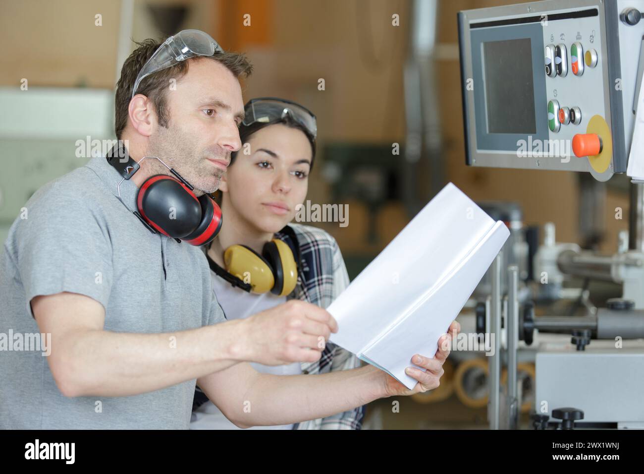 engineer training female apprentice on cnc machine Stock Photo