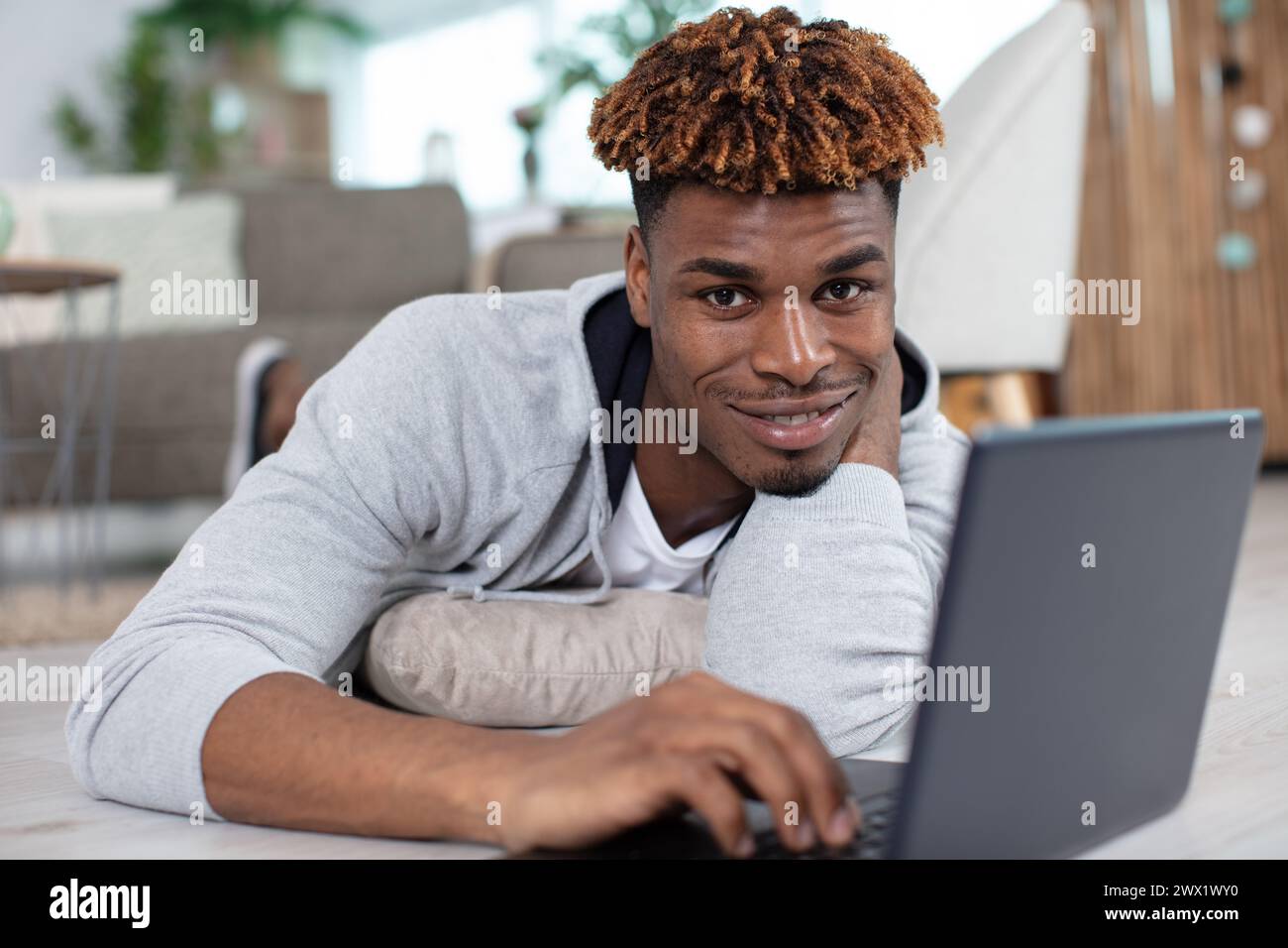happy man laying down on the floor using laptop Stock Photo
