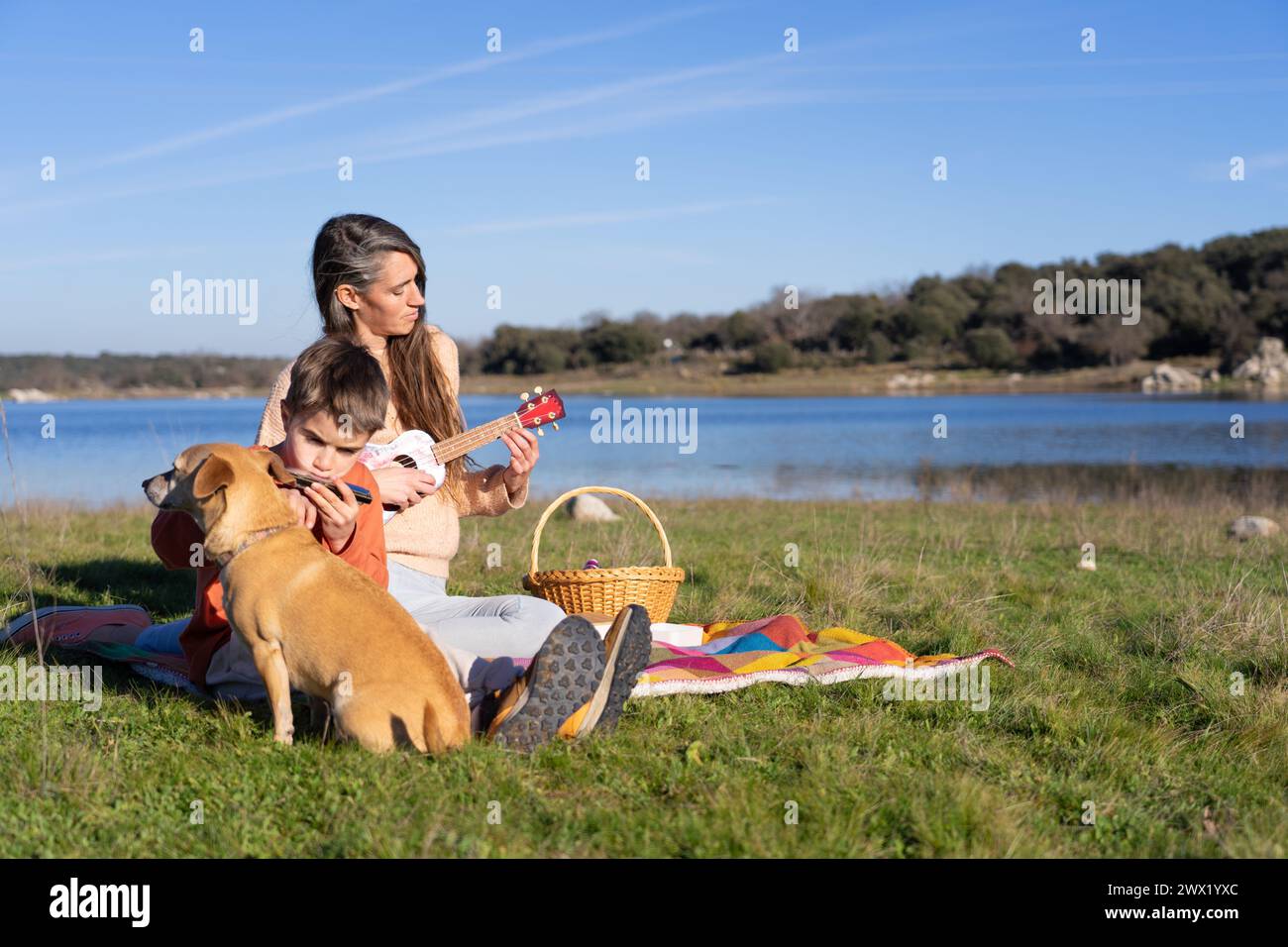 Picnic Instruments Mother and son playing instruments together on a picnic at a lake with ...