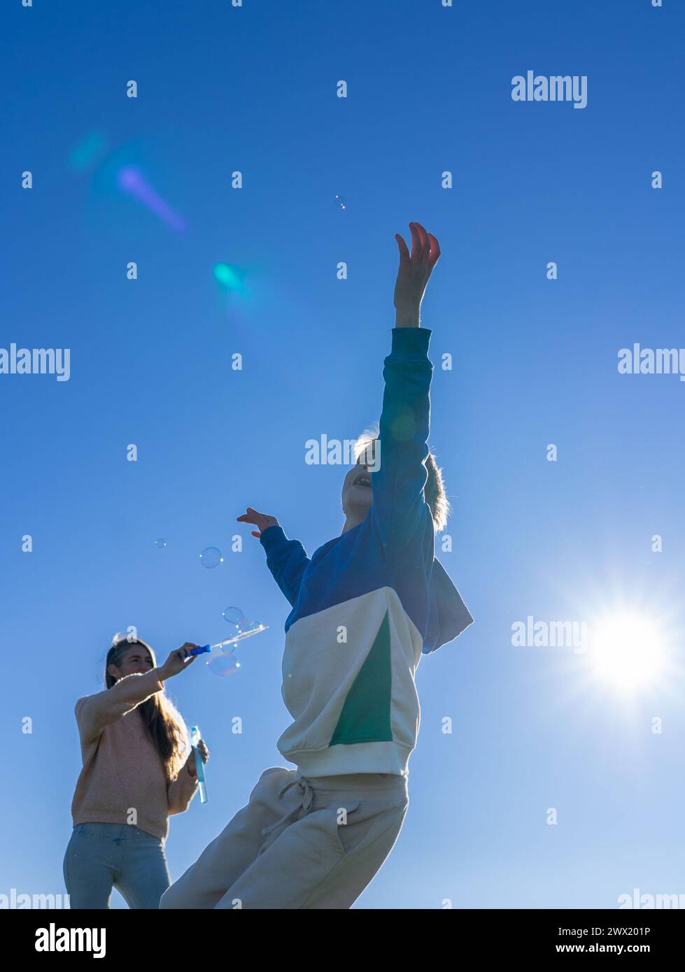 mother and son playing with soap bubbles outdoors Stock Photo