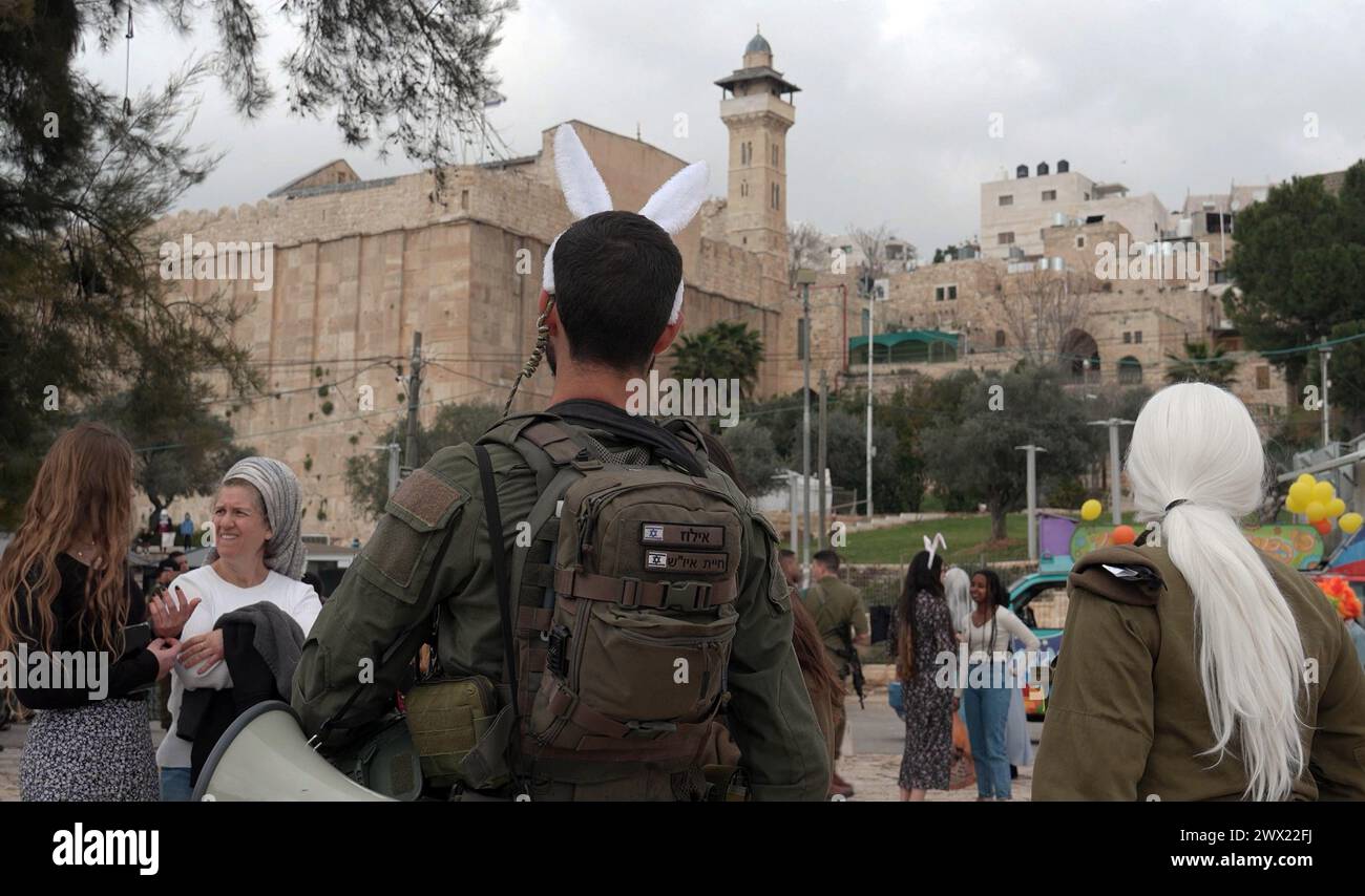 Jewish settlers wearing costumes dance as they march during the annual Purim parade as Israeli security forces secure the celebrations on March 24, 2024 in Hebron, Israel. Stock Photo