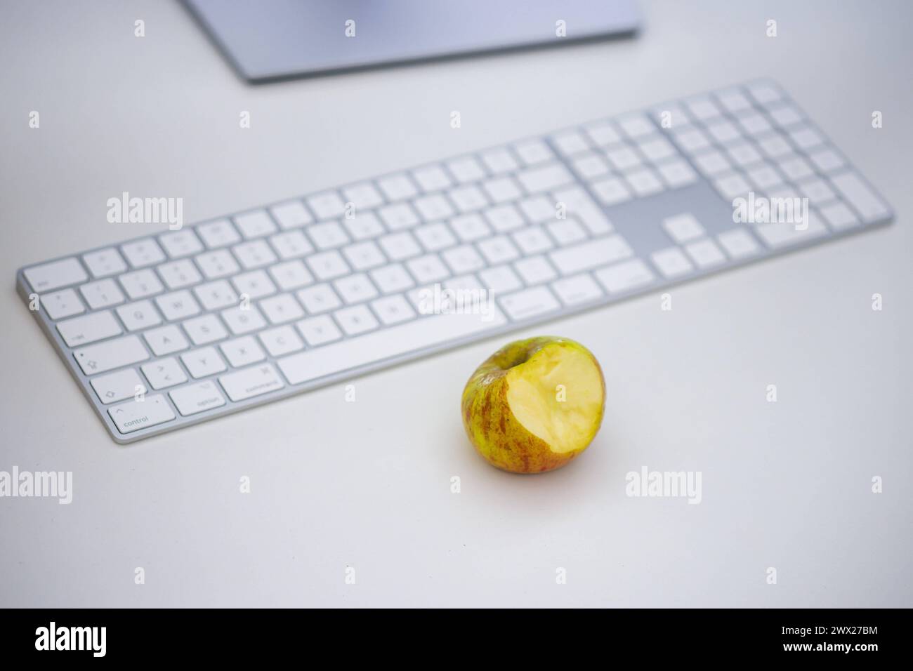 Symbolfoto zum Thema öÄÃ Gesunde Ernaehrung am Arbeitsplatz öÄÃ . Ein Apfel liegt neben einer Tastatur auf einem Schreibtisch im Buero. Berlin, 27.03. Stock Photo