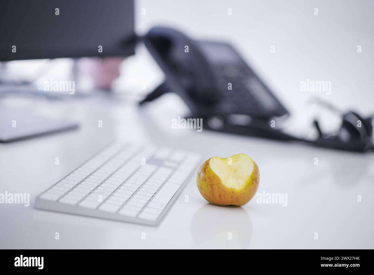 Symbolfoto zum Thema öÄÃ Gesunde Ernaehrung am Arbeitsplatz öÄÃ . Ein Apfel liegt neben einer Tastatur auf einem Schreibtisch im Buero. Berlin, 27.03. Stock Photo