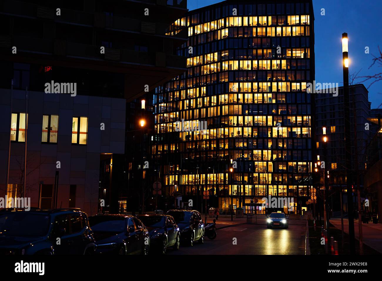 Office building lights up the evening with windows glowing in the dusk ...
