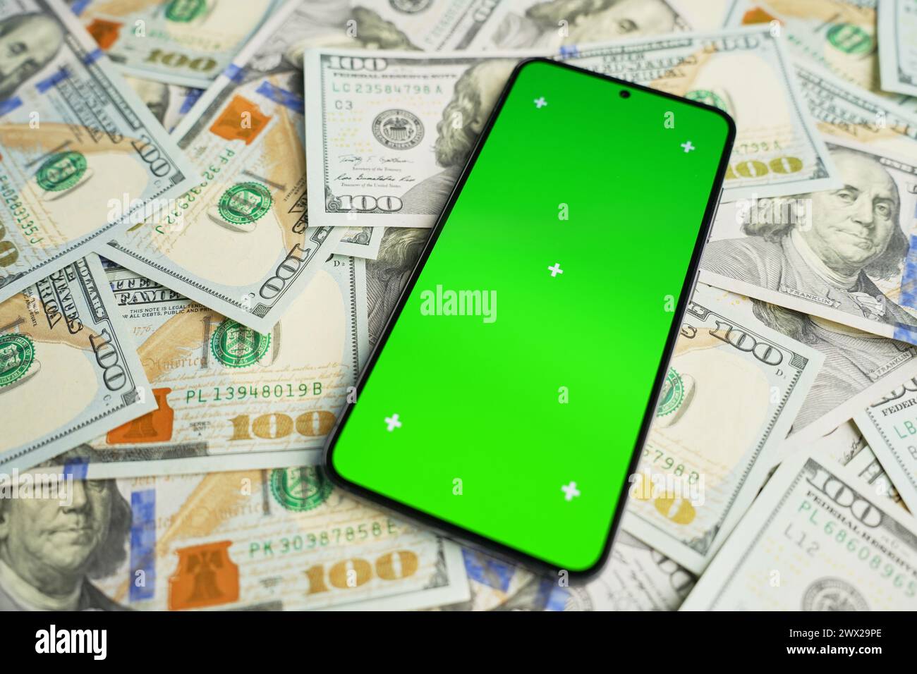 Smartphone with green screen on pile of dollar banknotes, top view. Concept of online earnings Stock Photo