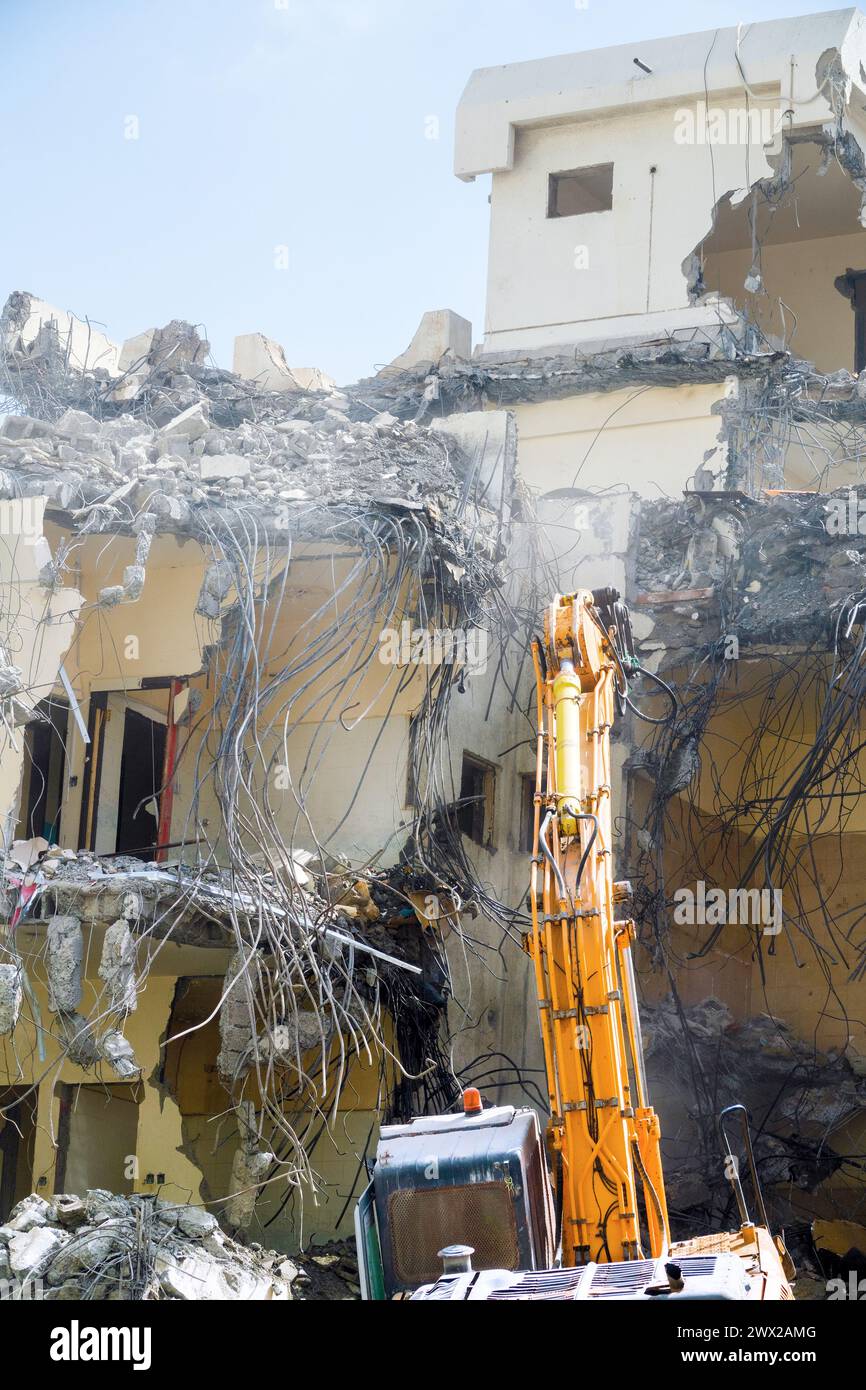 An special excavator destroys an old concrete house. Lots of twisted rebar sticking out, renovation programm Stock Photo