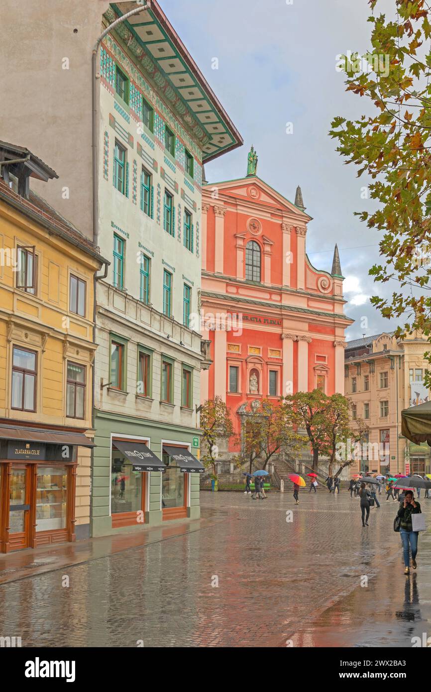 Ljubljana, Slovenia - November 4, 2019: People Walking With Umbrellas at Wet Cobbled Streets Rainy Fall Day in Capital City Centre. Stock Photo