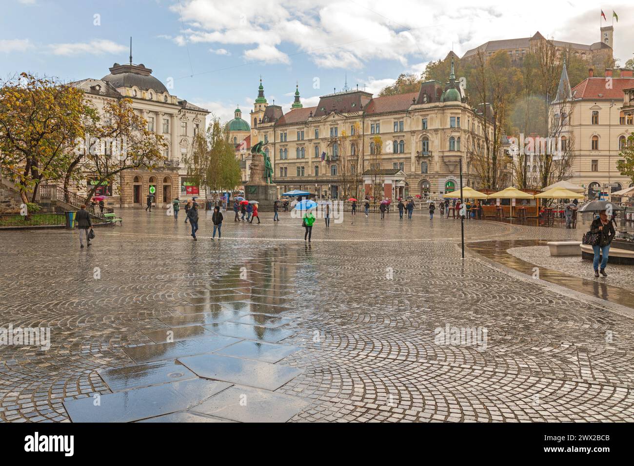 Ljubljana, Slovenia - November 4, 2019: People Walking at Wet Cobblestones Square Rainin Capital City Centre. Stock Photo
