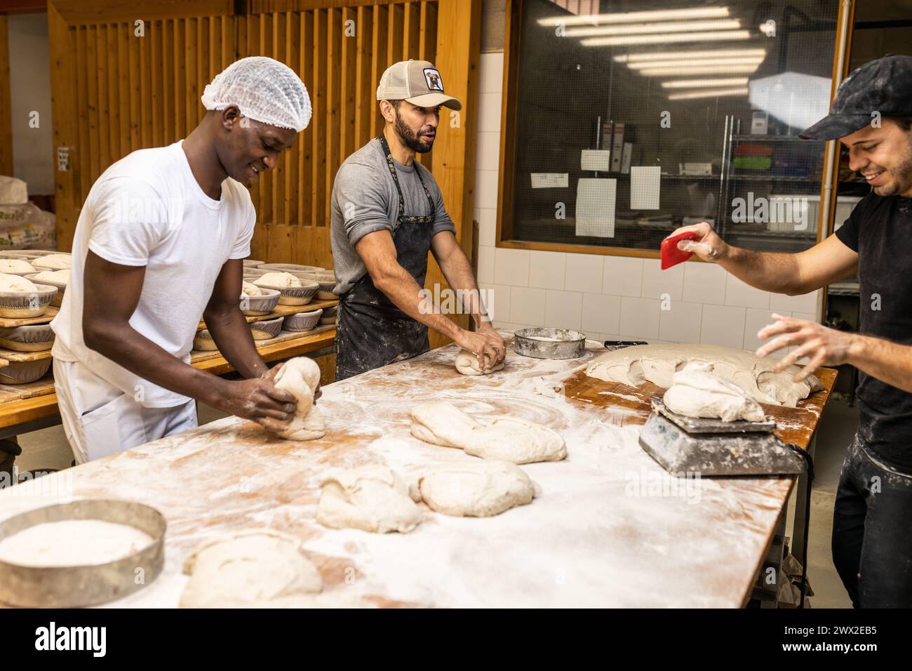 Multi-ethnic group of colleagues working in a bread factory, teaching the apprentices Stock Photo
