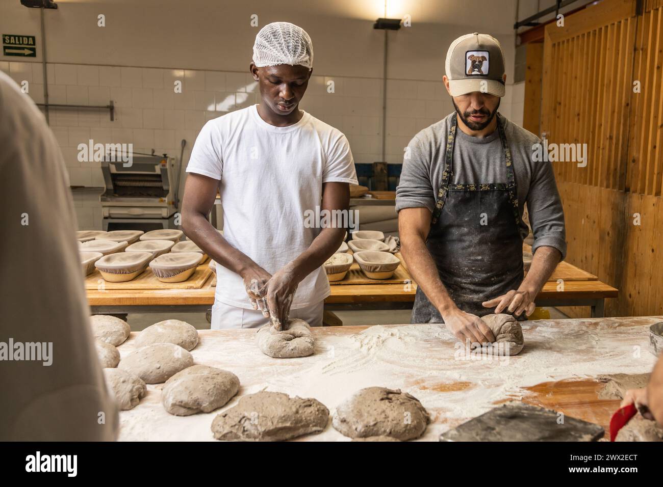 master baker teaching the technique to his apprentice in the bread factory Stock Photo