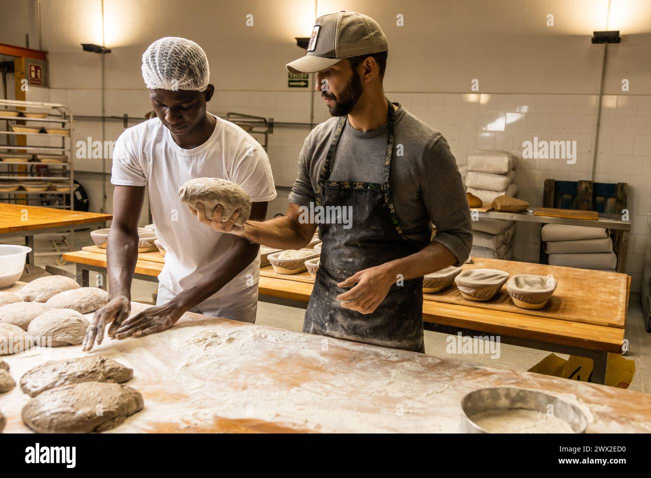 master baker teaching the technique to his apprentice in the bread factory Stock Photo