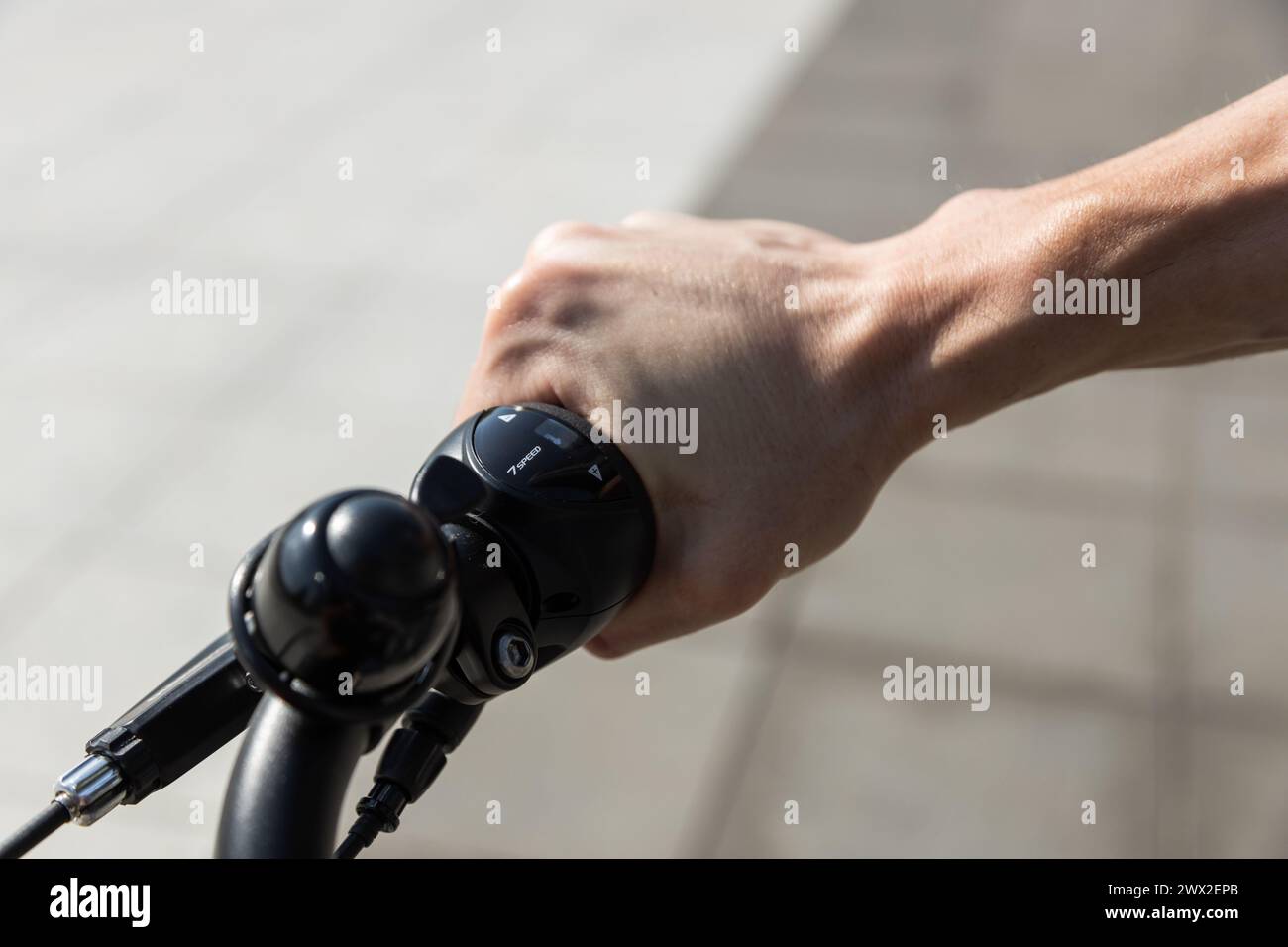 unrecognizable young man rides e-bike, hands holding bicycle handlebars Stock Photo