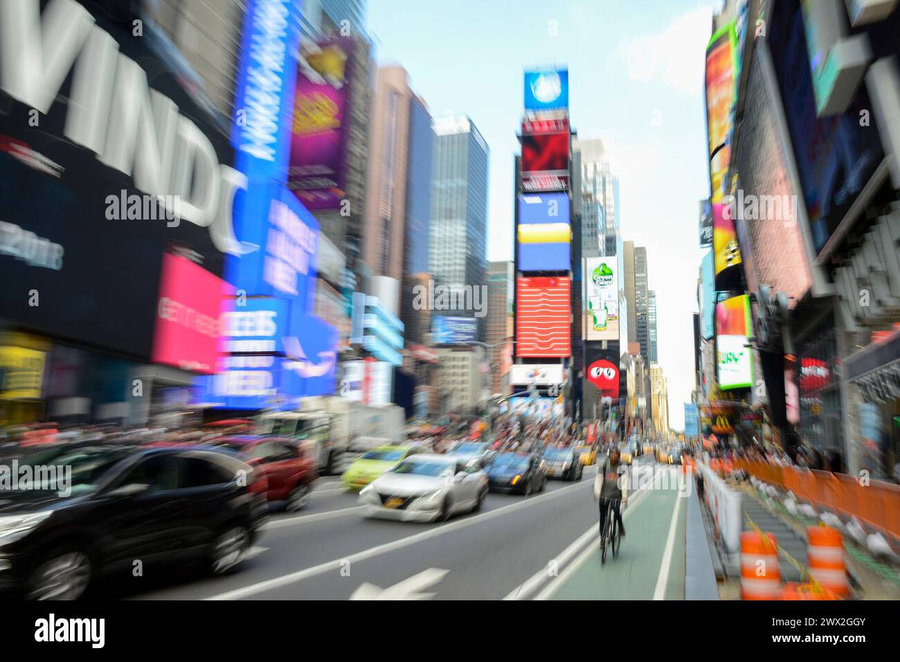 USA, New York City, Manhattan, Broadway and Times Square, bicycle, traffic and advertisement neon light billboards, image with blurred zoomed effect Stock Photo