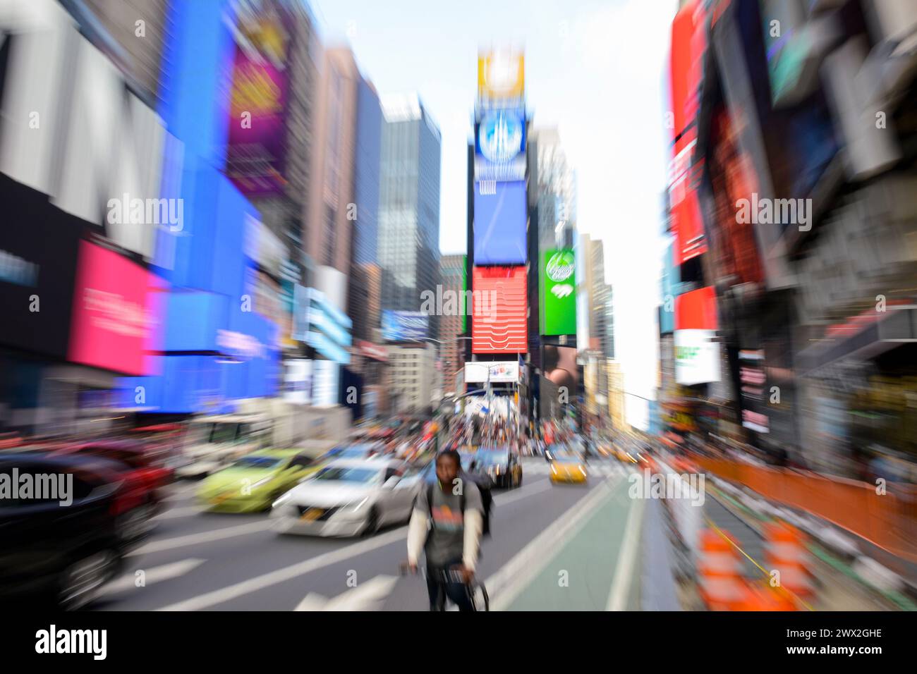 USA, New York City, Manhattan, Broadway and Times Square, bicycle, traffic and advertisement neon light billboards, image with blurred zoomed effect Stock Photo