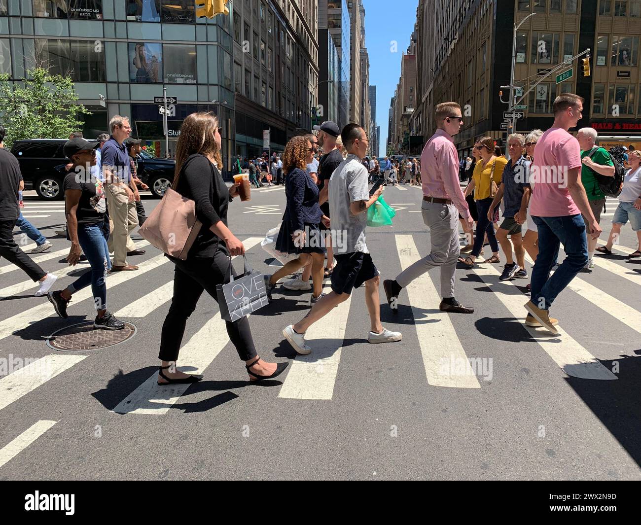 People make their way across the street, using the crosswalk in New York City Stock Photo