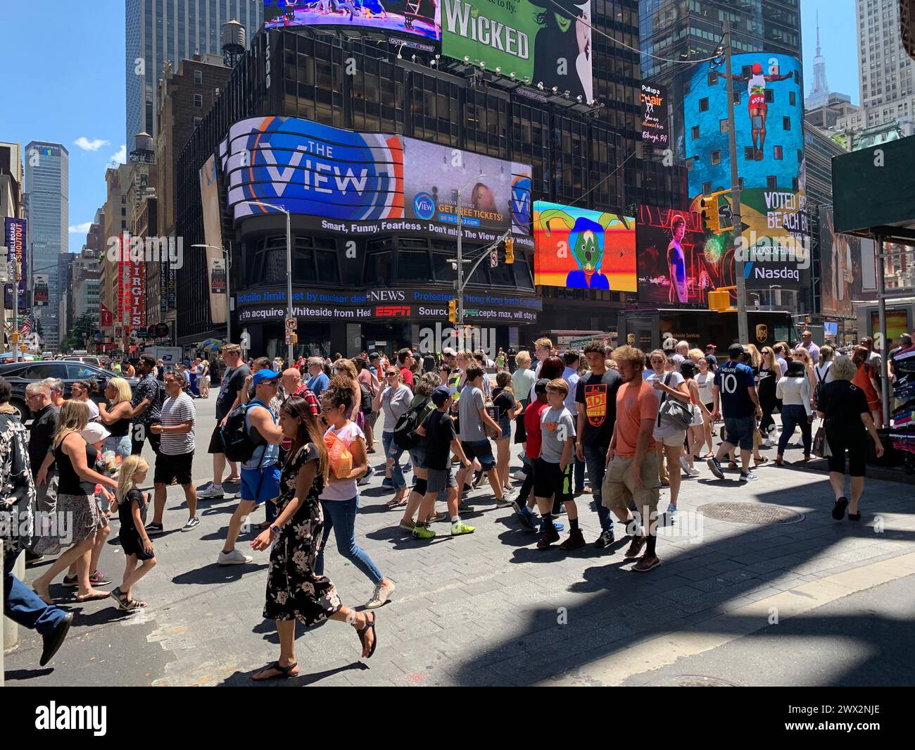 The streets of New York City's Times Square are crowded as pedestrians make their way through the crosswalk Stock Photo