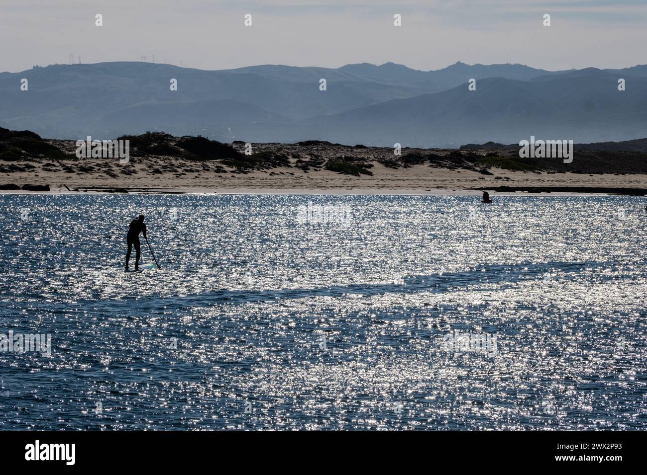 Standup paddle boarder at Morro Rock and Morro Bay, Pacific Ocean, Morro Bay, California, USA. Stock Photo