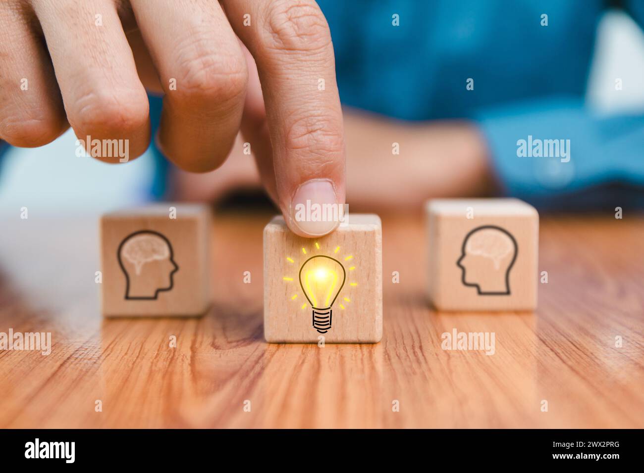 brainstorming creative idea and innovation. Hand putting over wooden cube block with light bulb icon on many people together having an idea symbolized Stock Photo