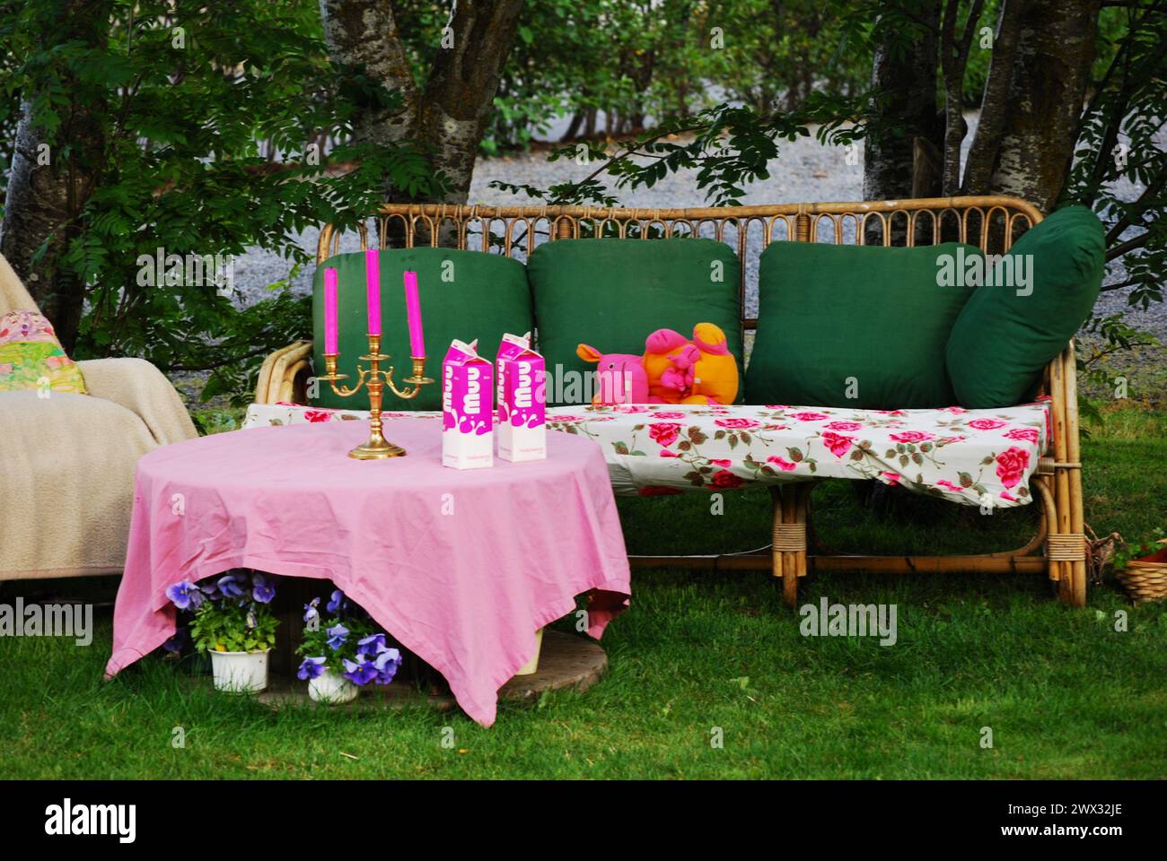 Wicker sofa in the garden with festively decorated table Stock Photo