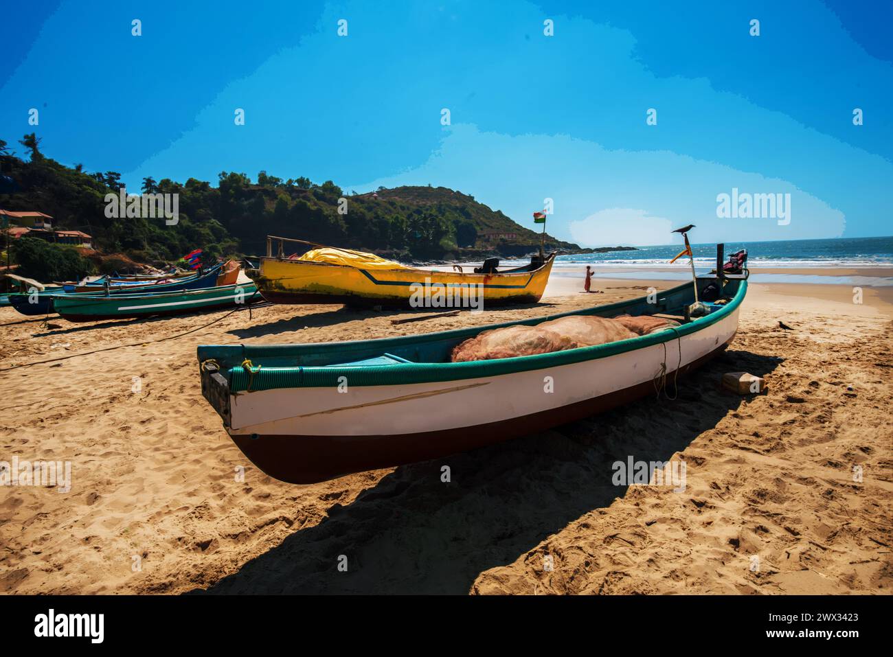 Awe view Fishing boats on beach ( there also many tourists) in fisshing village in Goa or Kerala ot Karnataka. People walking in distance and crow fly Stock Photo