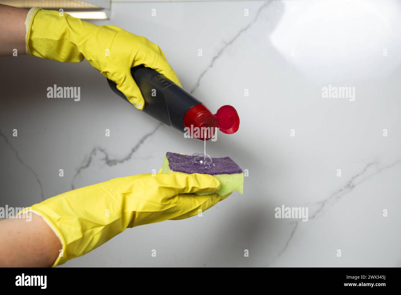 Female hands in yellow gloves with a sponge and detergent wash white ...