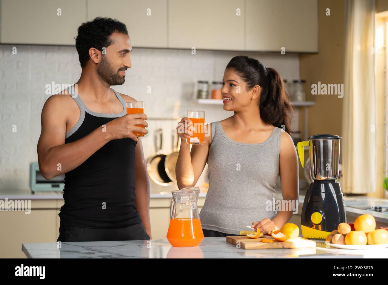 Joyful active healthy couples drinking nutritious orange juice after