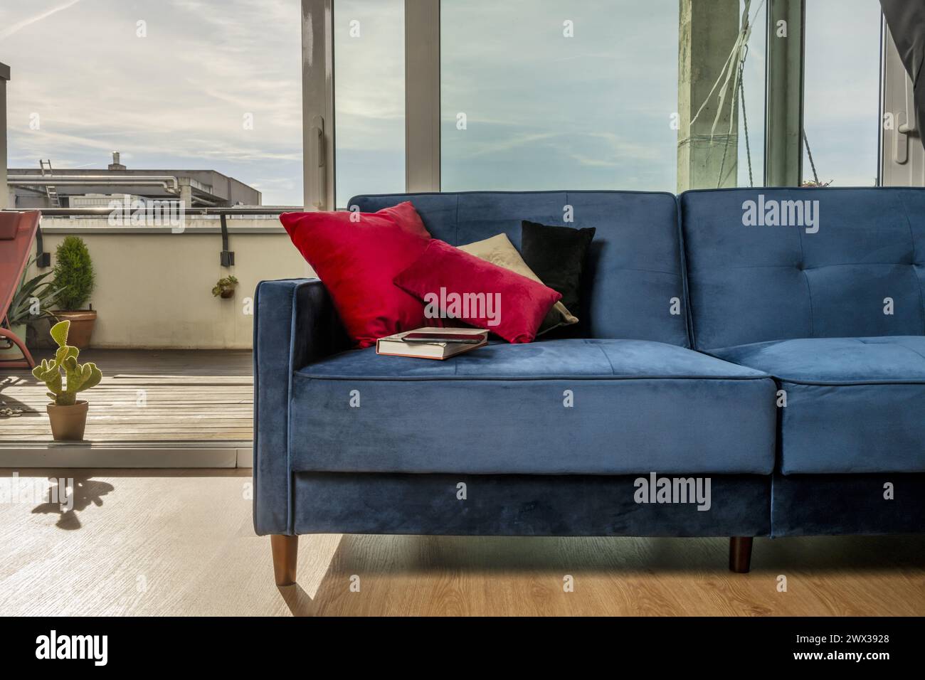 A blue velvet sofa next to a window that overlooks a terrace Stock Photo