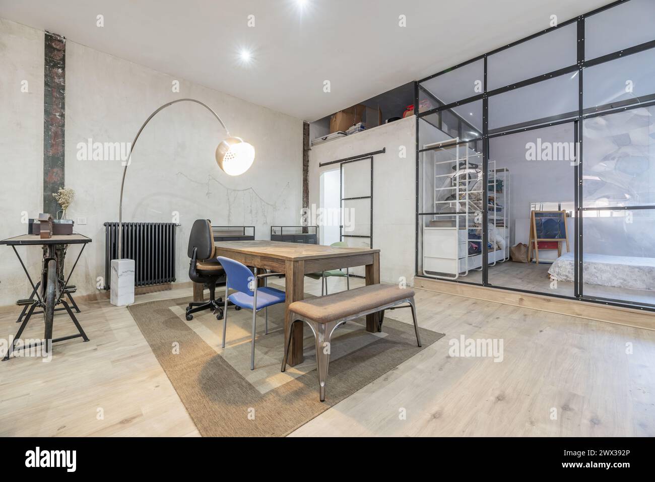 Open loft-style home with transparent partitions, industrial-style wood and metal furniture, and unpainted walls Stock Photo