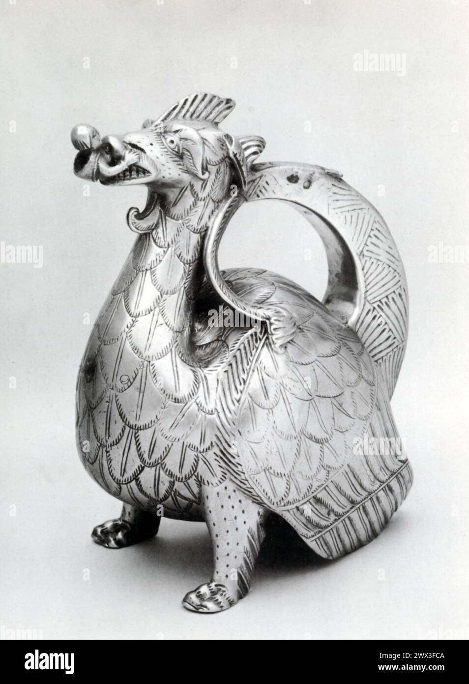 A bronze aquamanile in the form of a dragon swallowing a man, originating from Germany and dating back to the 12th-13th century. Aquamaniles, vessels used for washing hands at dining tables and in liturgical services, were common in the medieval period, often crafted into imaginative shapes, including animals and mythical creatures. Stock Photo