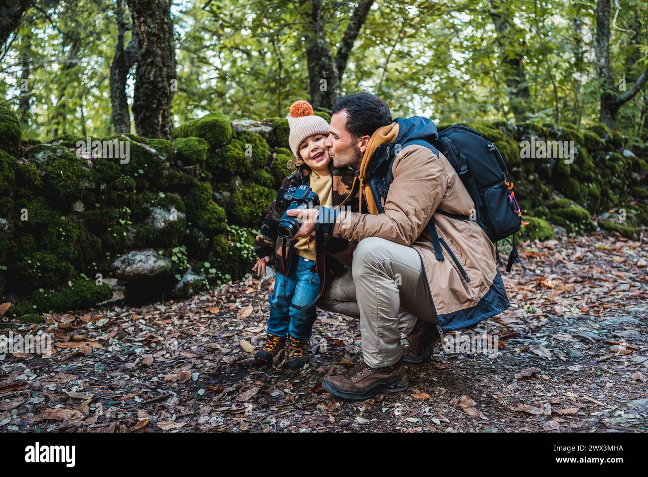 Photographer father and his fashionable son happy taking photos and lovingly kissing each other while enjoying the beautiful surroundings Stock Photo