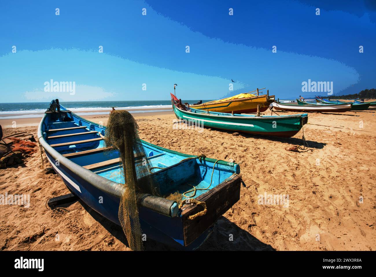Awe view Fishing boats on beach ( there also many tourists) in fisshing village in Goa or Kerala ot Karnataka. People walking in distance and crow fly Stock Photo